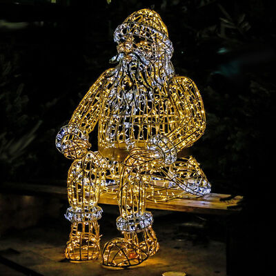 Ein berdimensionaler Weihnachtsmann aus einem Stahlgestell, der mit vielen weien und gelben Lmpchen dekoriert ist, sitzt als Deko in der Innenstadt