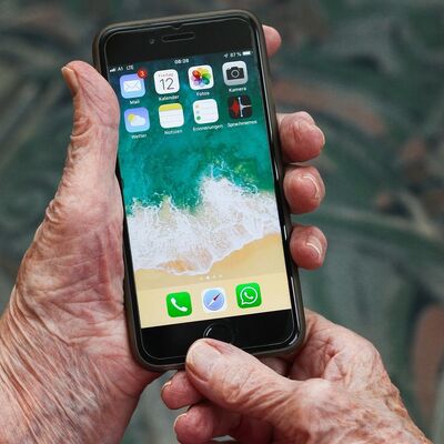 Ein alter Mensch hlt ein Smartphone in der Hand