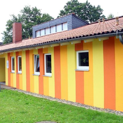 Die Außenwände der Kita Am Hopfengarten sind mit roten, orangenen und gelben Streifen angemalt.