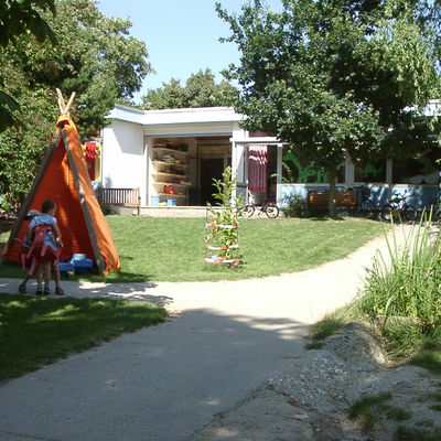 Außenanlage der Kita Kerschensteiner Weg mit großen Spielflächen und verschiedenen Pflanzen.