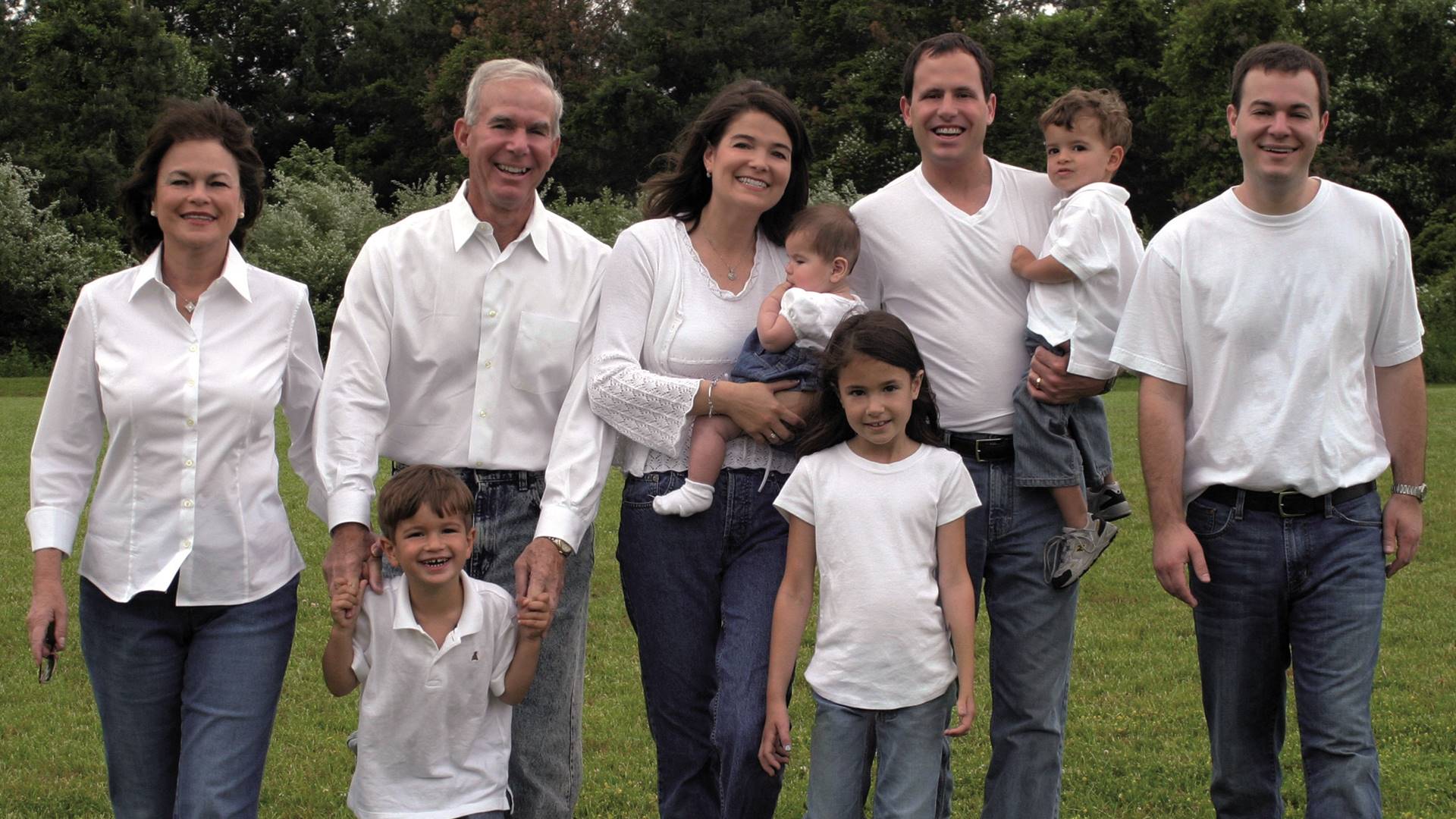 Eine Familie mit vier Kindern und fünf Erwachsenen steht zusammen. Alle tragen weiße Oberteile.
