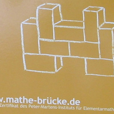 auf enem an eine Wand geschraubten Schild ist eine Zeichnung von ineinander gefügten Bausteinen, darunter steht "www.mathe-brücke.de, das Zertifikat des Peter-Martens-Instituts für Elementarmathematik 2009"