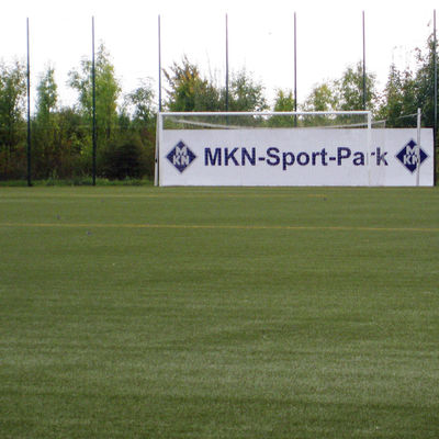 Blick über den BV Germania Kunstrasenplatz mit Tor und Werbung "MKN-Sport-Park"
