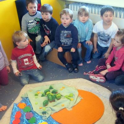 Die Kinder des Kindergartens St. Ansgar sitzen zusammen im Kreis und hören eine biblische Geschichte.