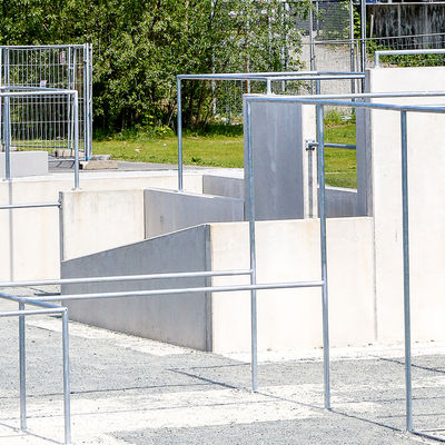 Auf einem Platz stehen mehrere Metallgestänge und kleinere Betonmauern, die zum Teil miteinander verbunden sind.