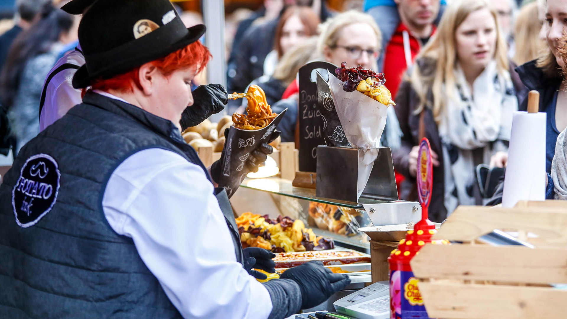 Link zum Infotext über das jährlich stattfindene Street Food-Festiva.
Bildmotiv: Blick auf einen Imbissstand, dahinter Kunden.