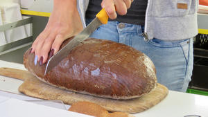 Ein Laib Brot wird mit einem Messer in zwei Hälften geschnitten.