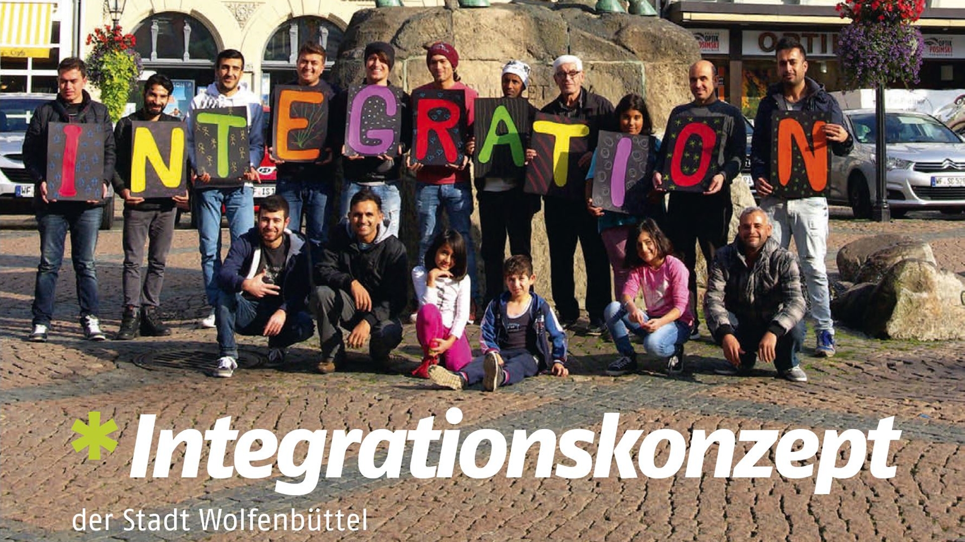 Gruppenfoto vor dem Reiterdenkmal auf dem Wolfenbütteler Stadtmarkt. Menschen halten Buchstaben hoch, auf dem insgesamt das Wort "Integration" zu lesen ist. am unteren Bildrand steht "Integrationskonzept der Stadt Wolfenbüttel".