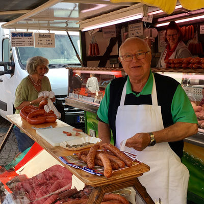 Ein Mann mit Schürze steht hinter einem Fleisch-Verkaufsstand auf dem Wolfenbütteler Wochenmarkt.