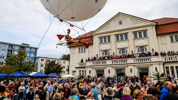 Auf dem Vorplatz des Lessingtheaters in Wolfenbüttel stehen viele Menschen. Über ihnen schwebt ein kleiner Heißluftballon.