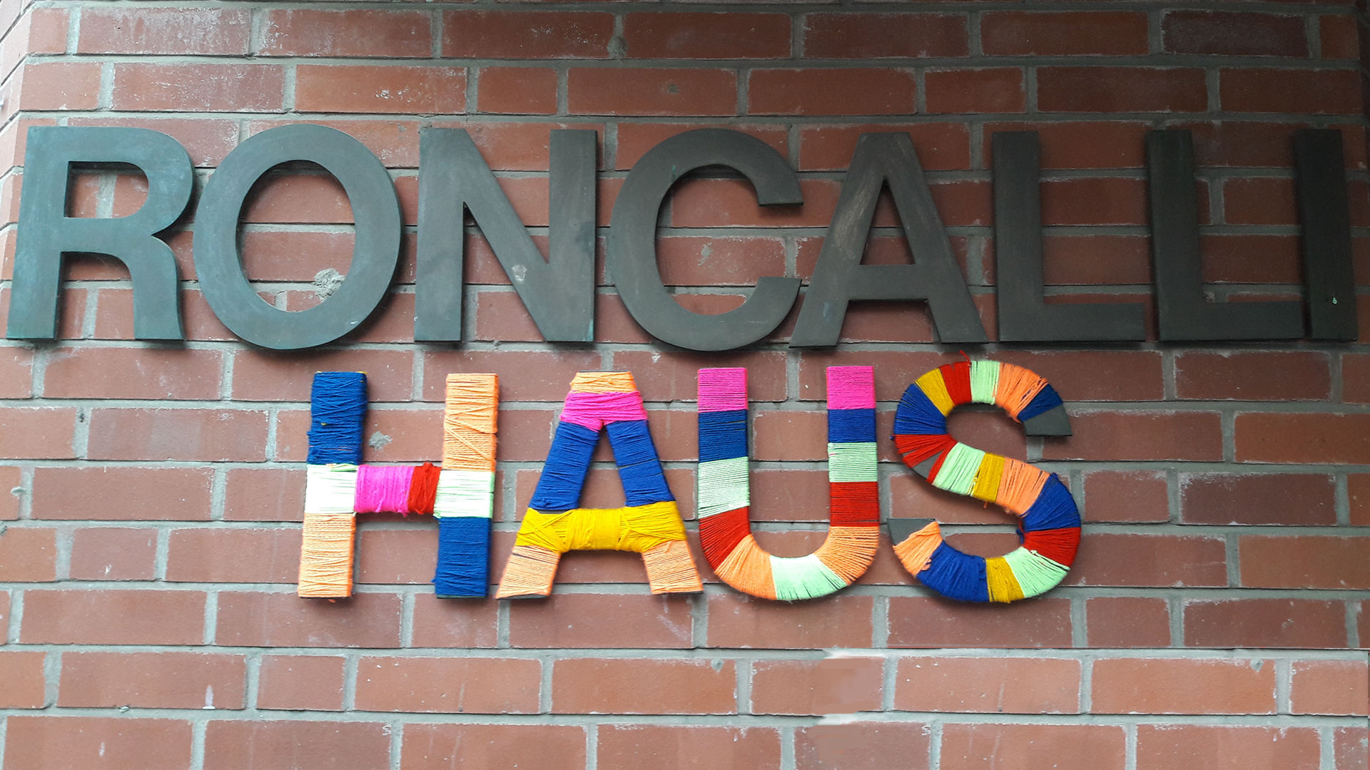 An einer Wand hängen Buchstaben, die die Wörter "Roncalli Haus" bilden.