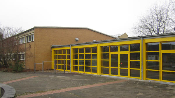 Fensterfront mit gelben Rahmen an einer großen Halle.