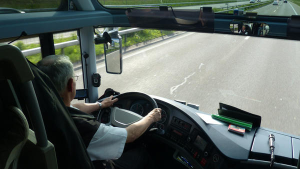 Busfahrer sitzt hinter einem Steuer eines fahrenden Busses.