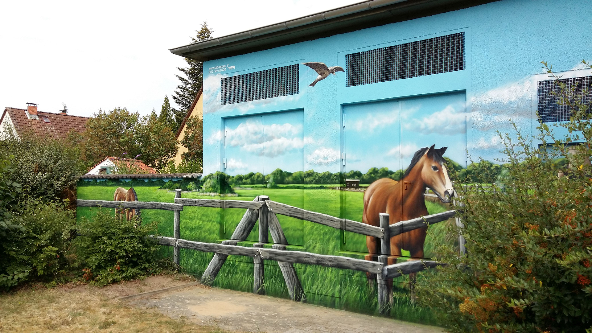 Die Wand eines kleinen Trafogebäudes ist realistisch bemalt. Die Szene zeigt eine Pferdekoppel mit einem Pferd.