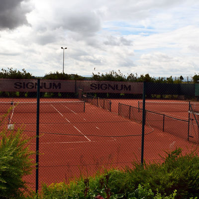 Rote Tennisplätze, die durch Zäune begrenzt sind.