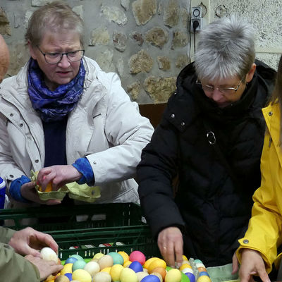Drei Frauen und ein Mann sortieren zum Teil bunt bemalte Eier.