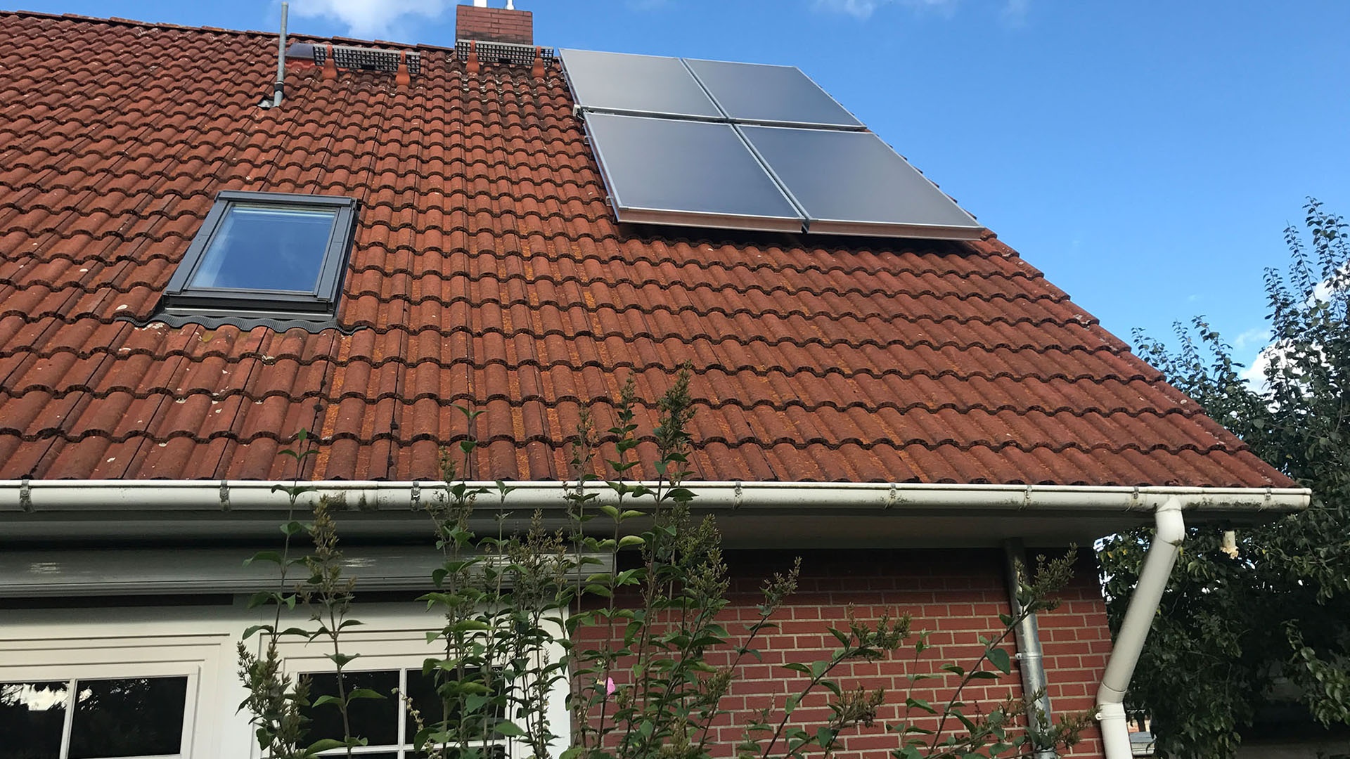 Auf einem Dach eines Wohnhauses sind vier Solarpaneele angebracht.