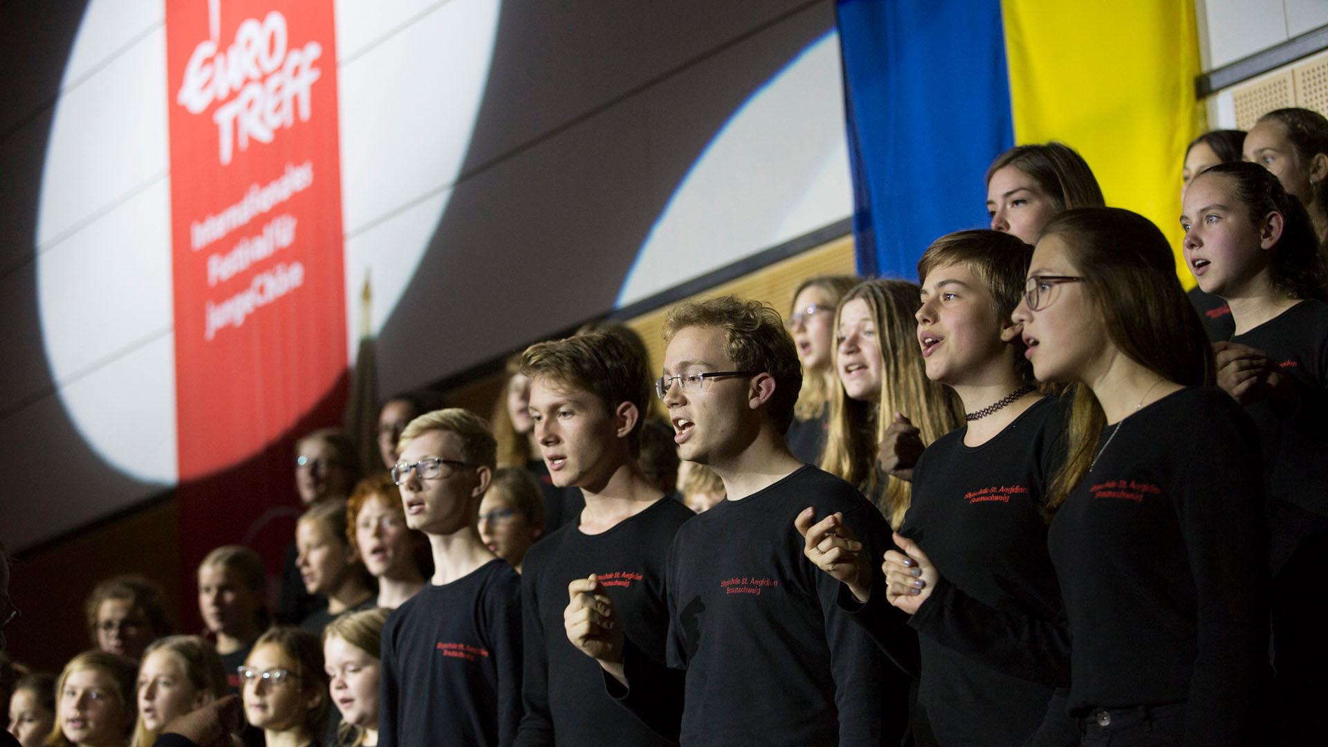 Link zu Veranstaltungsinfos zum Eurotreff.
Bildmotiv: Chor mit singenden Jugendlichen