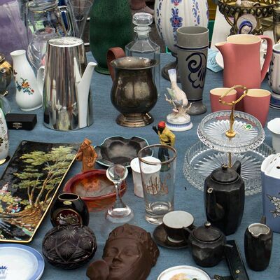Auf einem Tisch stehen viele Gläser, Teller, Krüge und Vasen