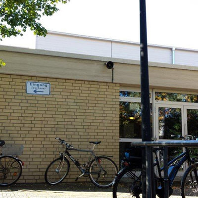 Vor dem Eingangsbereich einer Sporthalle stehen drei Fahrräder.