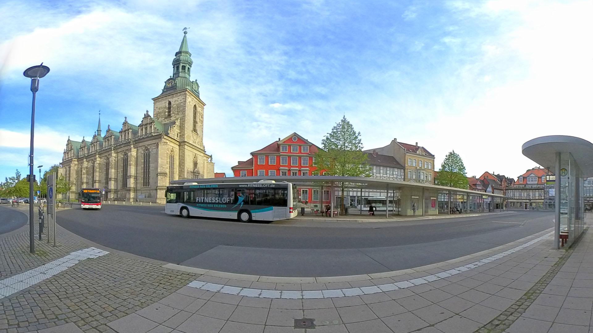 Weitwinkelaufnahme vom Kornmarkt: im Hintergrund die Hauptkirche und Häuserzeile, im Vordergrund die Bushaltestelle und zwei Busse.