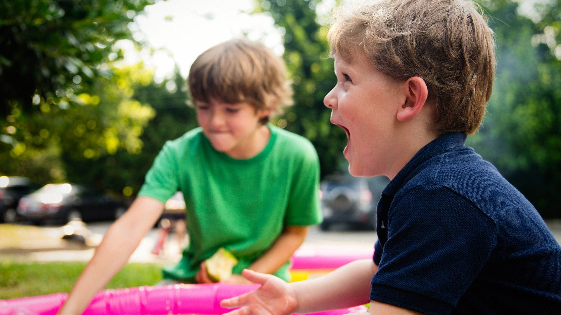 Zwei Jungen im Grundschulalter spielen miteinander, ein Junge lacht vor Freude.