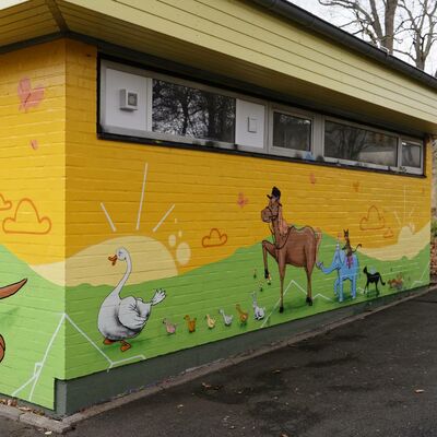 Grün-gelbe Fassade mit gemalten Tieren.Känguruhs, Enten, Pferd und Katzen.