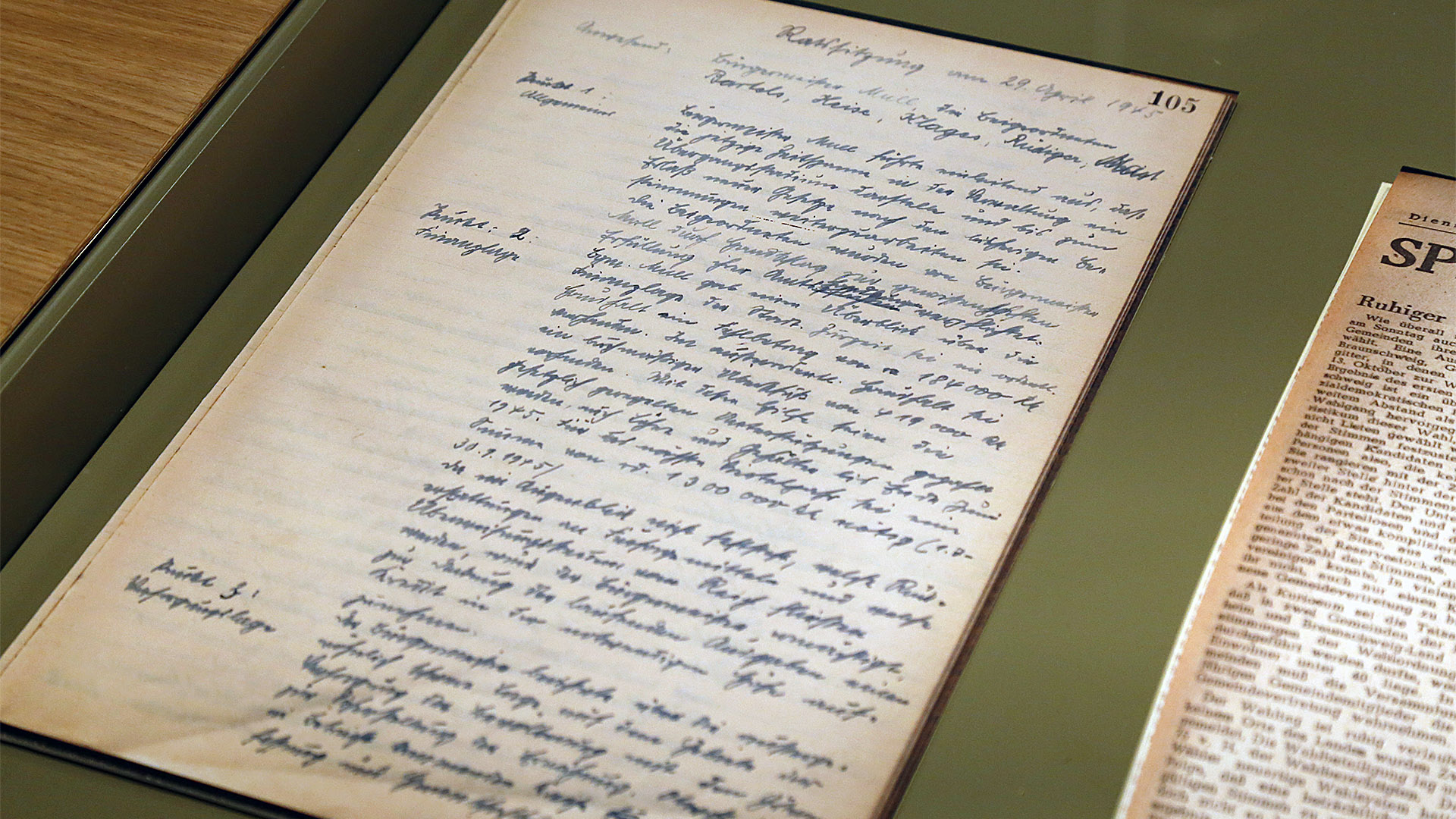 Auf dem Bild ist ein großer handschriftlicher Zettel zu sehen. Es handelt sich um ein Sitzungsprotokoll vom ersten Treffen Wolfenbütteler Politiker nach Ende des Zweiten Weltkrieges. Es fand am 29. April 1945 statt.