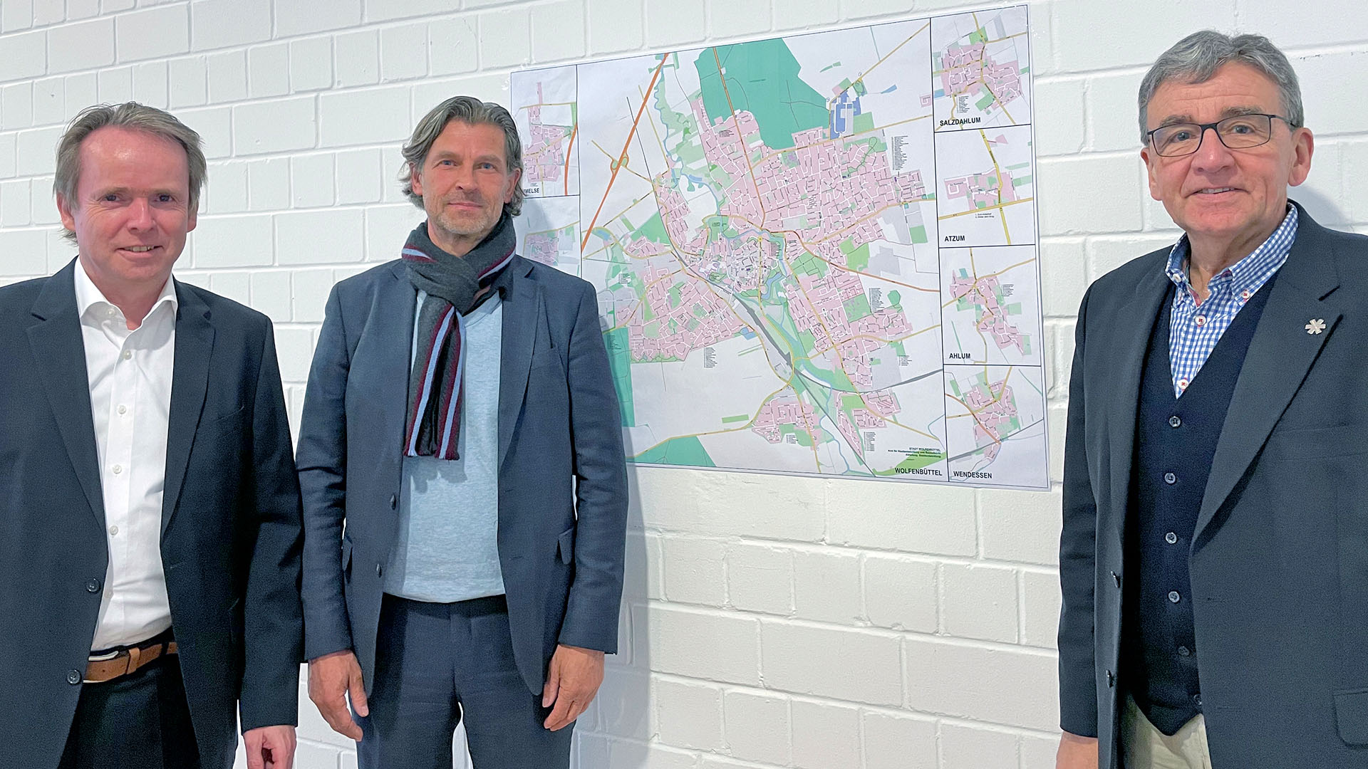 Marcus Klein und Heinrich Altmiks stehen mit Bürgermeister Thomas Pink vor einem Stadtplan von Wolfenbüttel, der an der Wand hängt.