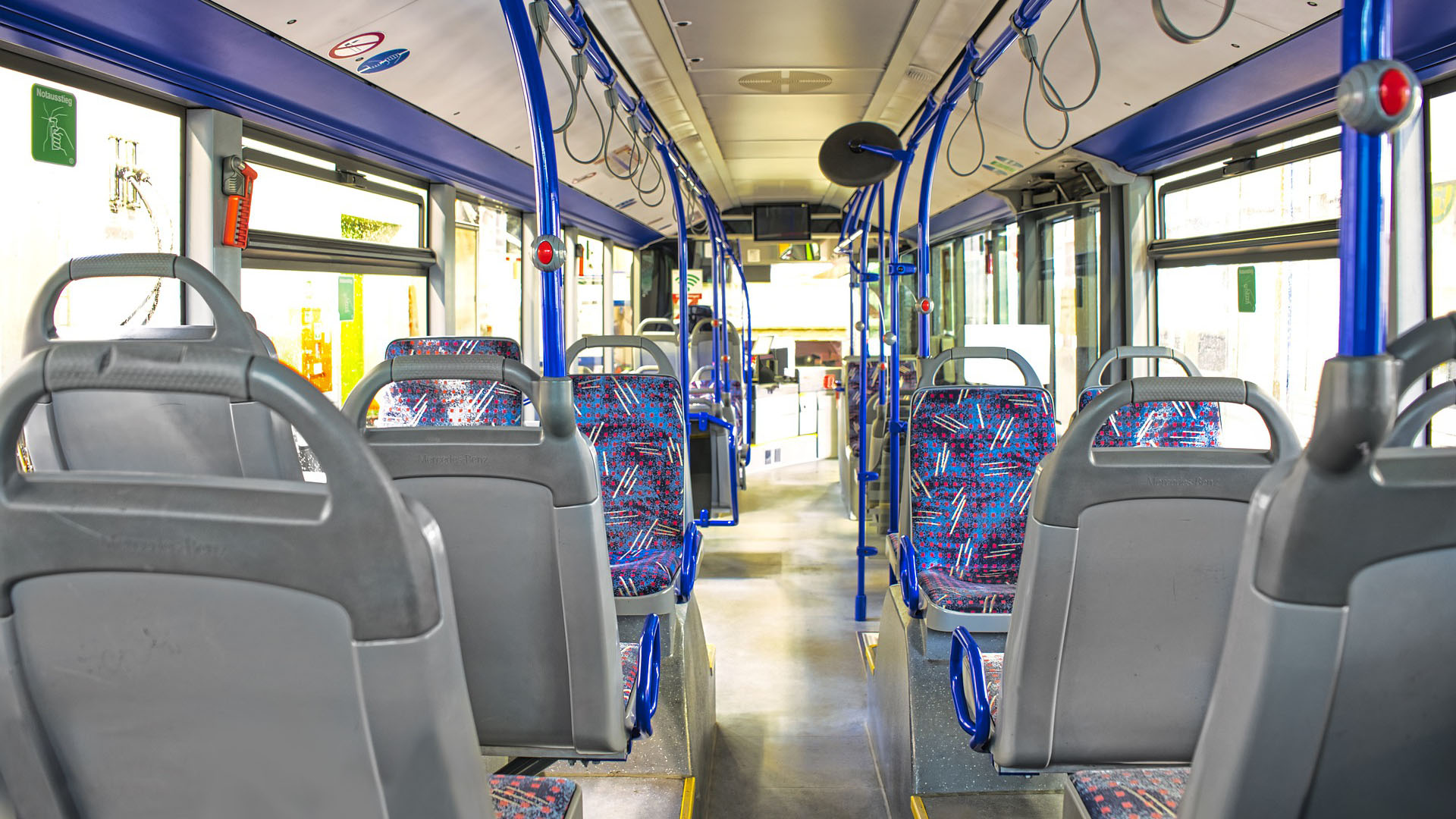 Blick durch den Mittelgang eines Linienbusses, rechts und links sind leere Sitzplätze.