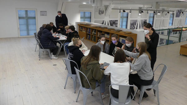 Das Foto zeigt Schülerinnen und Schüler des Theodor-Heuß-Gymnasiums, die an zwei Tischen sitzen und in Büchern lesen.
