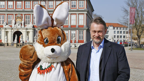 Ein Mann steht neben ein als Osterhase verkleideten Person vor dem Schloss Wolfenbüttel.