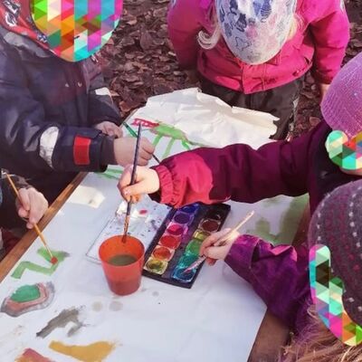 An einem Tisch sitzen mehrere Kinder und tuschen mit bunten Farben.