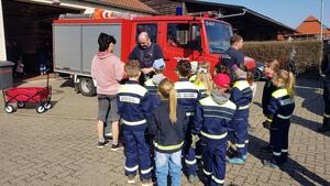 Mehrere Kinder und Erwachsene stehen vor einem Feuerwehrfahrzeug.