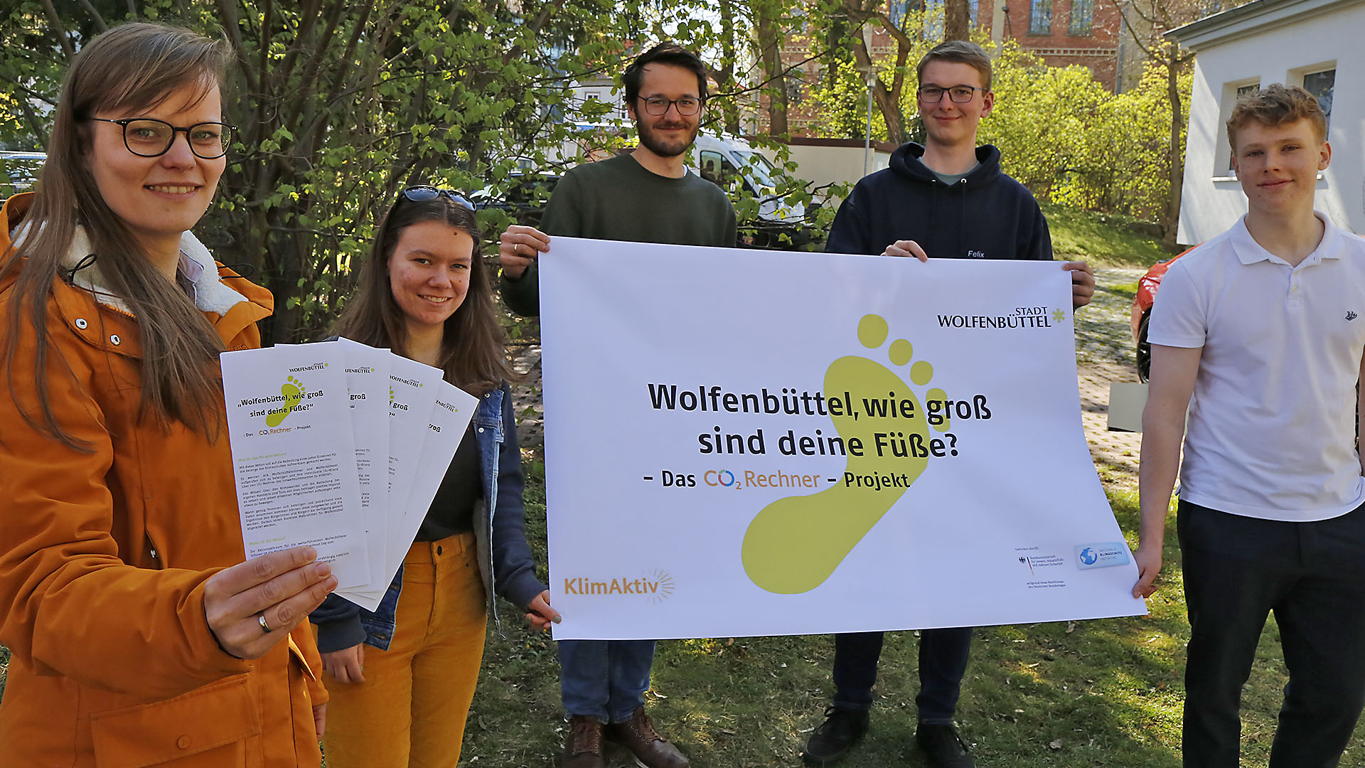 Zwei Frauen und drei Männer halten Flyer und ein Plakat mit der Aufschrift "Wolfenbüttel, wie groß sind deine Füße" - Das CO2-Rechner-Projekt