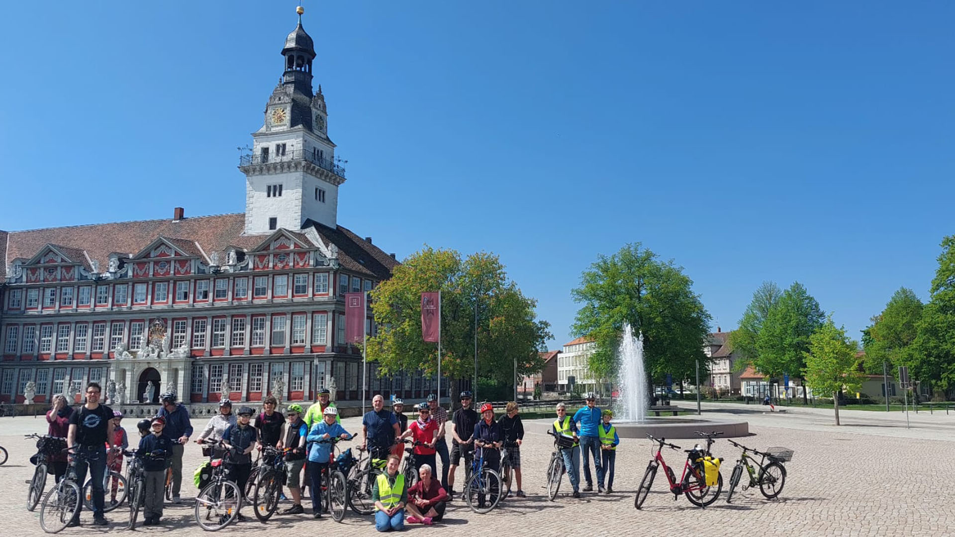 Auf dem Schlossplatz vor dem Schloss stehen mehrere Radfahrerinnen und -fahrer mit ihren Rädern.