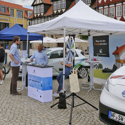 Infostände mit Besuchern auf dem Schlossplatz, im Vordergrund ein Elektroauto