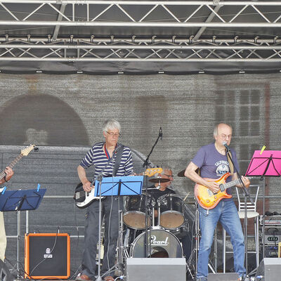 Drei Männer stehen auf einer Bühne auf dem Schlossplatz und machen Musik