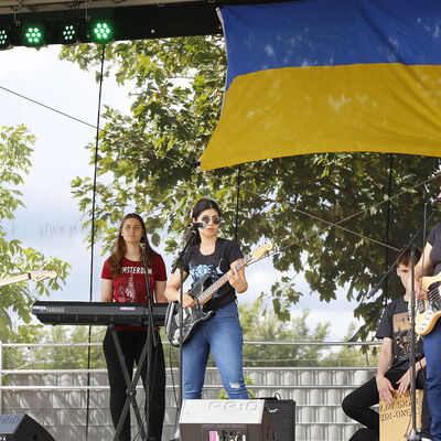 Eine Musikband spielt auf der Bühne beim Ukraine-Fest am Fümmelsee, über ihnen hängt eine große blaugelbe Flagge
