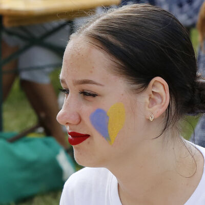 Eine junge Frau beim Ukraine-Fest am Fümmelsee hat ein blaugelbes Herz auf einer Wange.