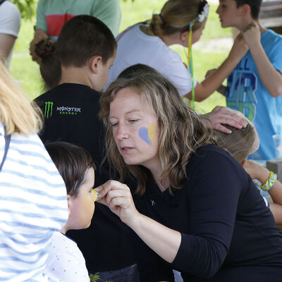 Eine Frau schminkt einem Jungen beim Ukraine-Fest am Fümmelsee das Gesicht blaugelb.
