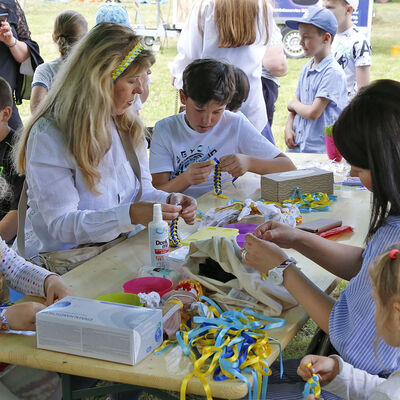 Kinder und Frauen flechten beim Ukraine-Fest am Fümmelsee blaugelbe Bänder