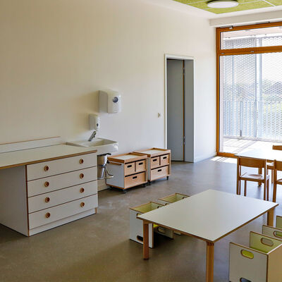 Ein Raum mit kleinen Stühlen und Tischen in einer Kindertagesstätte.