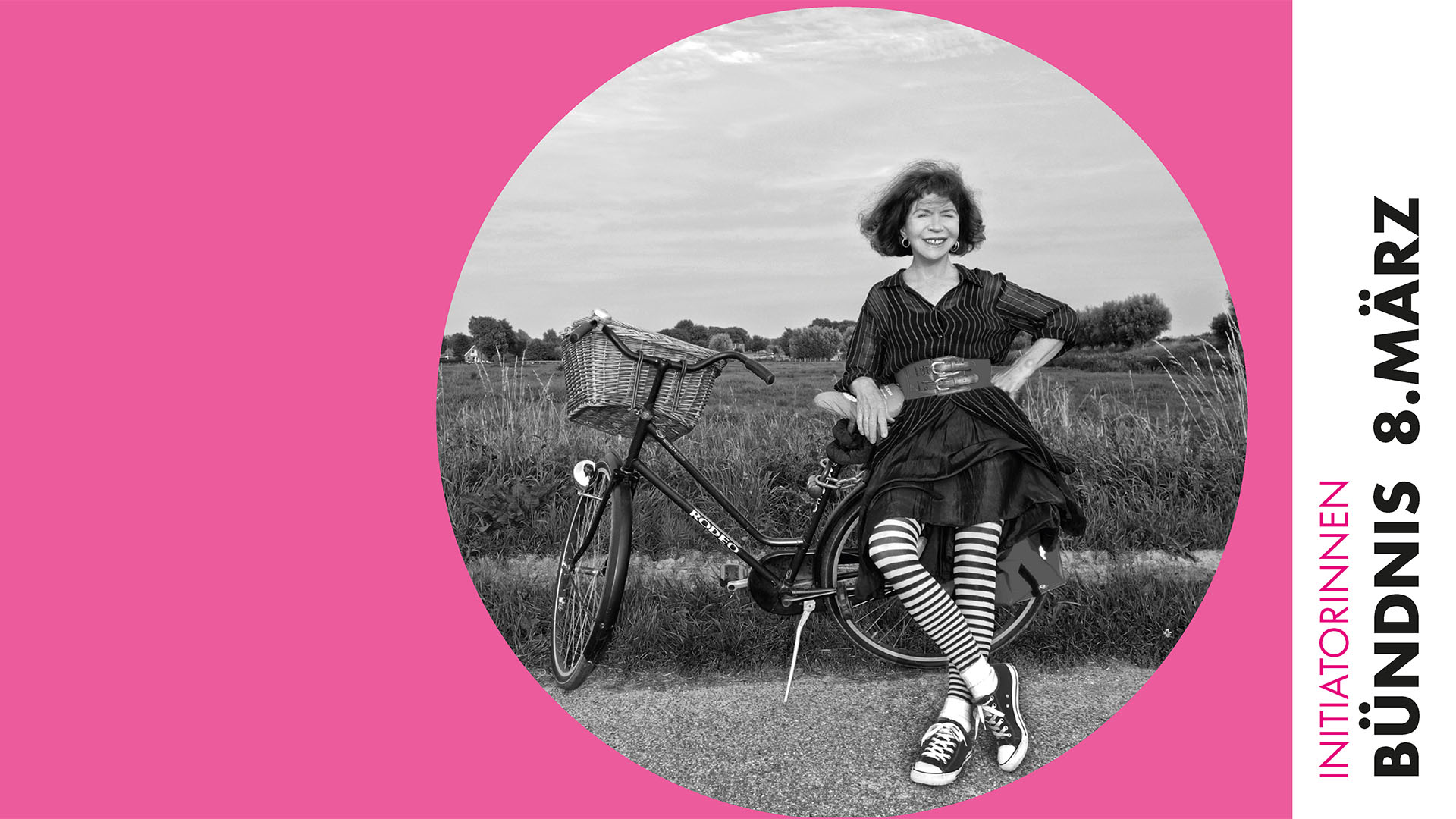 In einem runden Bildauschnitt lehnt sich eine Frau an einem Feldrand an ein abgestelltes Fahrrad. Außerhalb des Auschnittes befindet sich ein rosafarbener Rahmen mit der Beschriftung "Innitiatorinnen Bündnis 8. März"