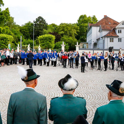Zum Großen Zapfenstreich versammeln sich Schützen auf dem Schlossplatz, eine Musikkapelle spielt im Hintergrund