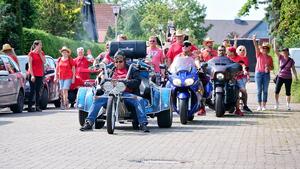 Eine Gruppe Motorräder und vielen Personen mit roten T-Shirts..