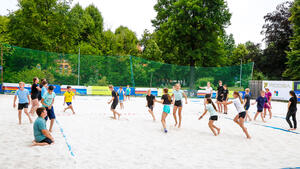 Mehrere Personen spielen mit einem Ball im Sand.