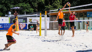 Mehrere Personen spielen mit einem Ball im Sand.