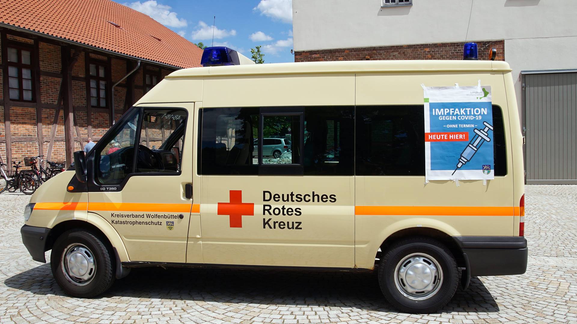 Kleinbus vom Deutschen Roten Kreuz mit einem Plakat mit Hinweisen zur Impfaktion gegen Covid-19 "Ohne Termin" und "heute hier".