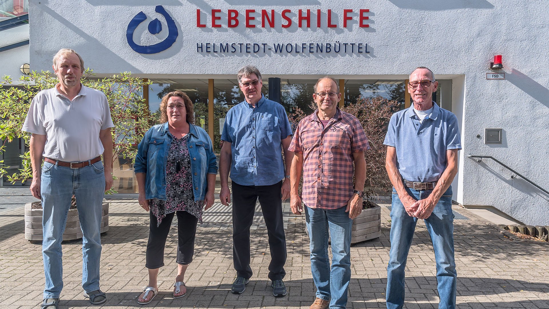 Vier Männer und eine Frau stehen vor dem Haus mit der Beschriftung Lebenshilfe Helmstedt-Wolfenbüttel